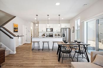a dining area with a table and chairs and a kitchen in the background
